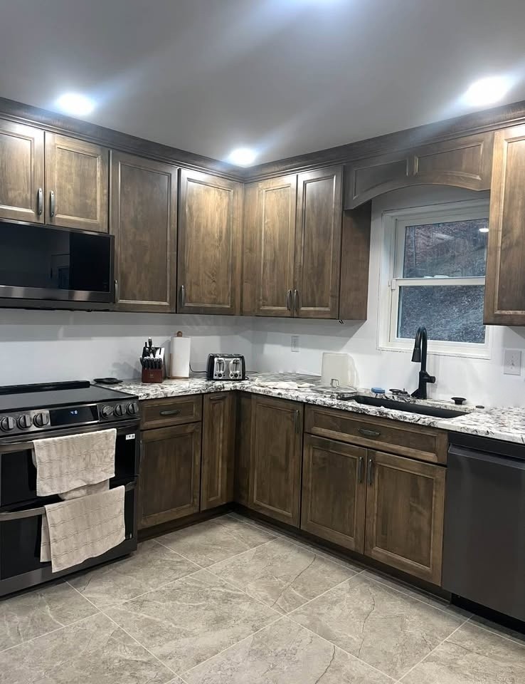 A medium-brown stained kitchen corner with an arched window hood over the stove, a sink, and a dishwasher