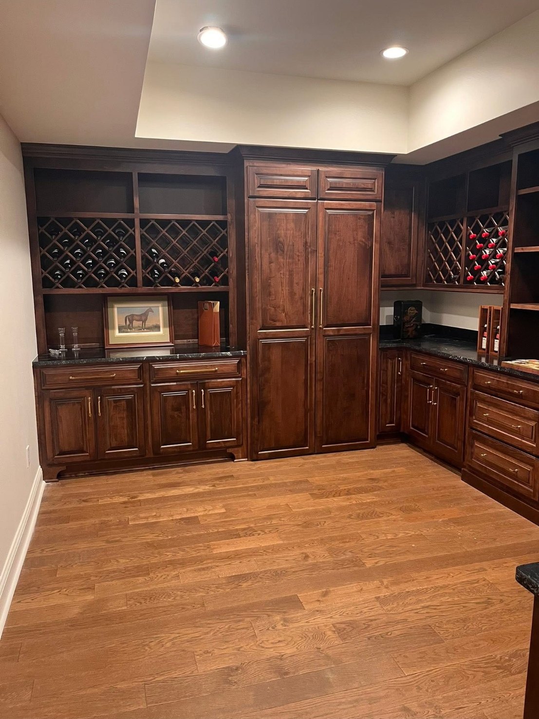 A dark-stained wine room with diamond wine racks and open shelves flanking a tall pantry cabinet