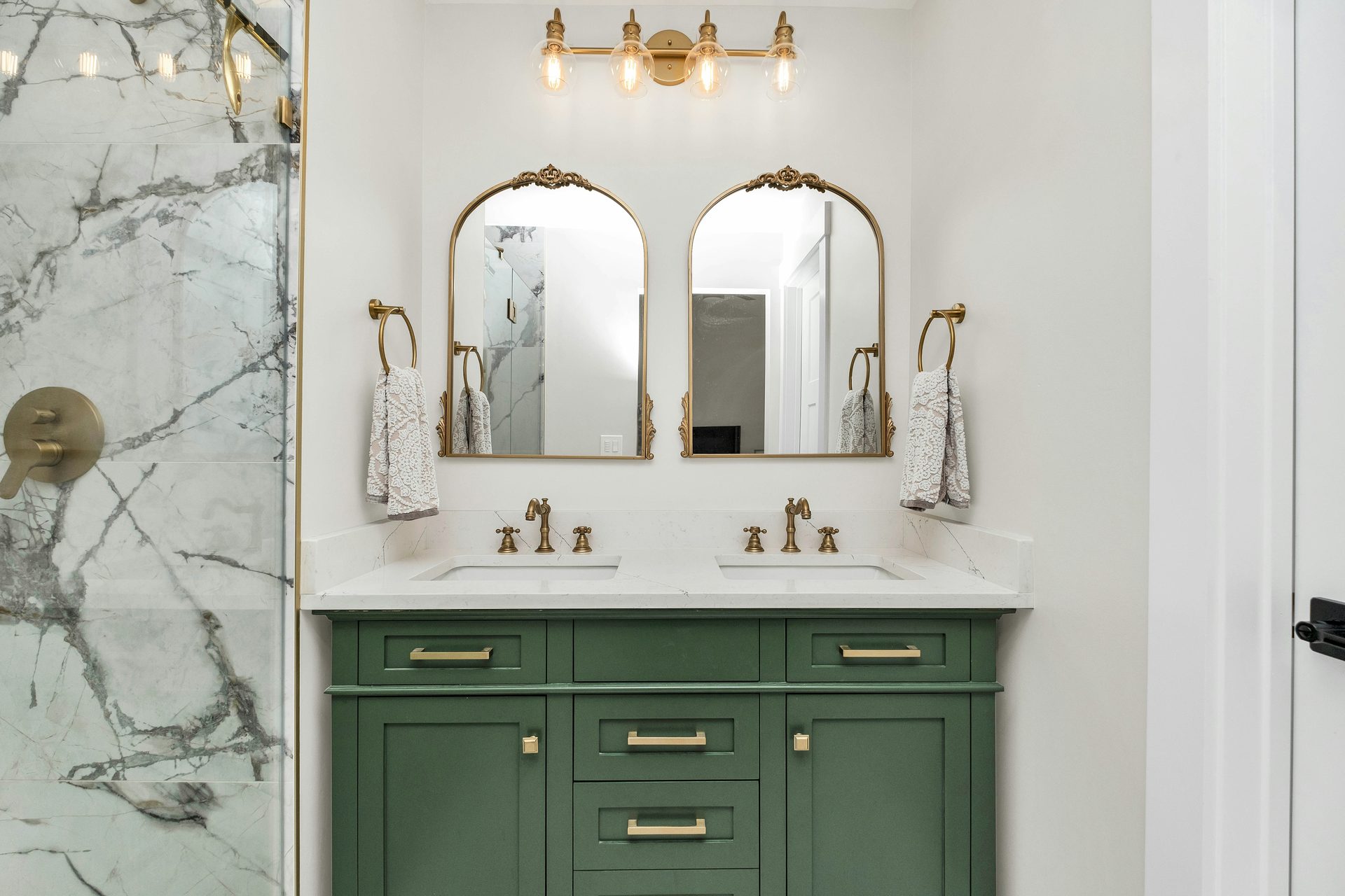A sage-green painted double-sink bathroom vanity with brass hardware